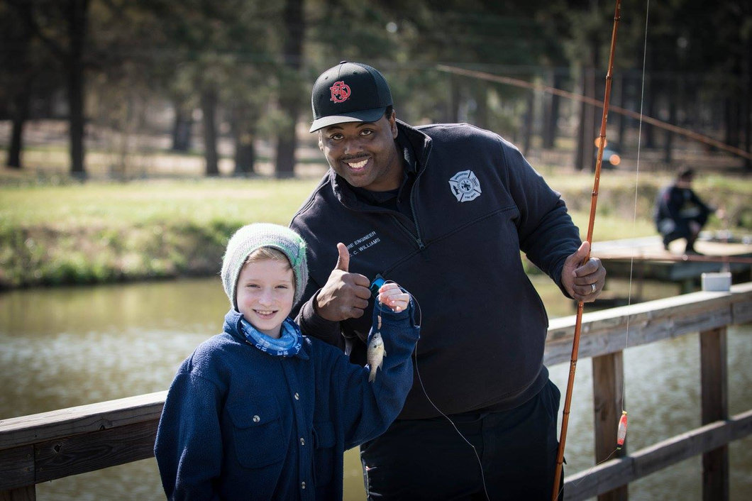 A young angler showing a fish alongside a Bass Life community volunteer
